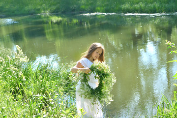 Girl in beautiful wreath on summer meadow near the river. Feast of Ivan Kupala.Midsummer. Earth...