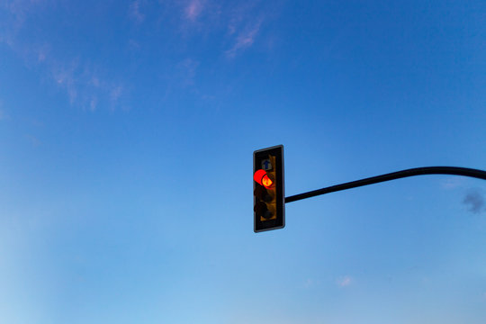 Red traffic light against blue sky