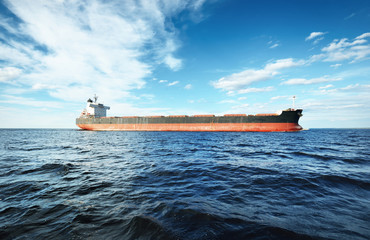 Large bulk carrier (cargo ship) sailing in an open sea from Europoort. Clear blue sky with cirrus clouds. Rotterdam, Netherlands. Global communications, logistics, industry theme © Alex Stemmer