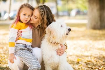 Beautiful, happy young mother with little girl and dog outdoor.
