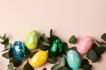 Colorful glossy easter eggs witih leafs of the natural eucalyptus.Trendy pastel background.Copy space for text or design.