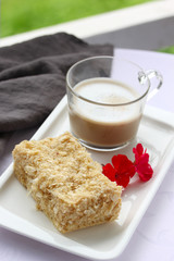 Desserts, a cup of coffee and napoleon cake on a white plate on the table. Purple flower....