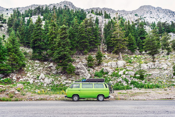 Vintage camper van on the road to rocky mountains.