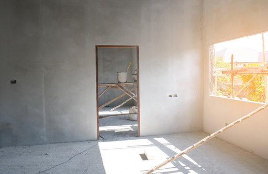 Install door in new house open window with orange warm light. raw concrete plaster on wall.