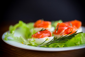 boiled eggs with salted red fish and salad leaves
