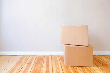 two cardboard boxes in empty room with wall background and copy space, moving in new flat concept mockup