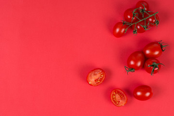 Fresh ripe cherry tomatoes on a branch on a red background, monochrome, trend bright background, top view, copy space