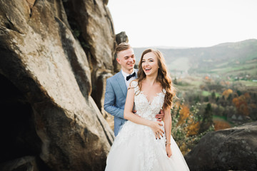 Fototapeta na wymiar Happy wedding couple posing over beautiful landscape in the mountains