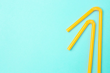Yellow cocktail straws on a blue background with copyspace.