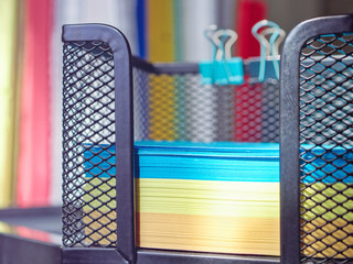 Composition of stationery. Multi-colored paper sheets for notes are in a metal tray. 