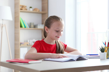 little girl reads a book at home
