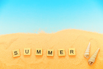 Summer vacation background, sand, shells, words Summer. Concept of a summer vacation on the beach with a blue copy of the space