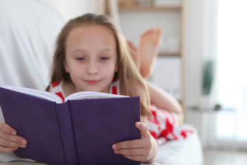 little girl reads a book at home
