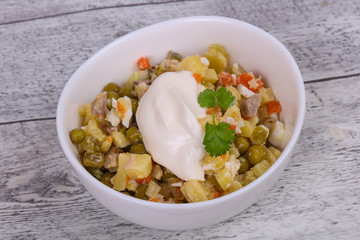 Traditional Russian salad with chicken in the white bowl