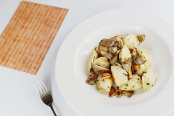 dumplings with mushrooms in a white plate, next to salt and pepper on the table