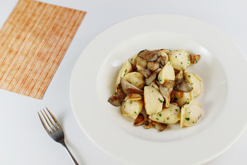 dumplings with mushrooms in a white plate, next to salt and pepper on the table