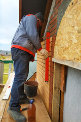 The wall of the house is made of silicate red brick, the master puts the brick on the arch of the door.