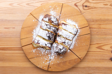 fruit strudel on a wooden board sprinkled with icing sugar. delicious pastries
