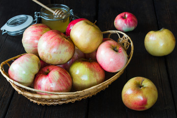 Apples in a basket and honey on a black background.