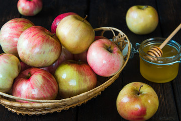 Apples in a basket and honey on a black background.