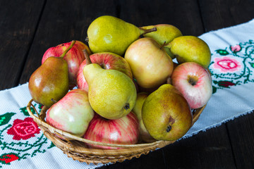 Apples and pears in a basket and honey on a black background.
