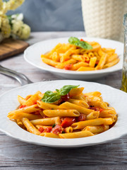 Penne pasta with fresh tomatoes and basil on wooden table. Traditional italian dish