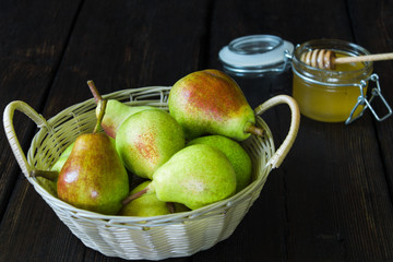 Apples and pears in a basket and honey on a black background.
