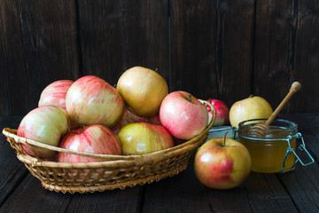 Apples in a basket and honey on a black background.