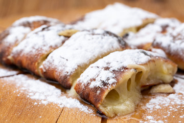 fruit strudel on a wooden board sprinkled with icing sugar. delicious pastries