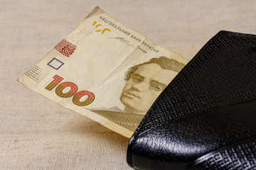 Ukrainian hryvnia in a black wallet on a gray background.