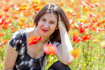 Portrait of beautiful young girl in poppies field outdoor. Blooming Poppies memory symbol.