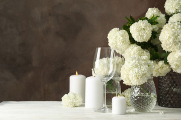 Composition with hydrangea flowers and candles against brown background. Romantic evening