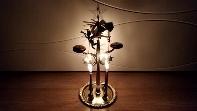 Christmas decoration with burning candles. Endless video of angel chimes rotating in dark. Time lapse footage with New Year golden decor