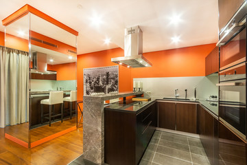 Orange kitchen with a marble counter, equipped with cooker, oven, fridge