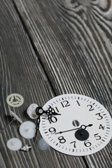 Watch mechanism details. Gears, arrows and dial. On brushed pine boards.