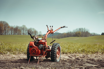 A small hand tractor, walk-behind tractor, plows the land. Work on the field. The concept of agriculture and industry