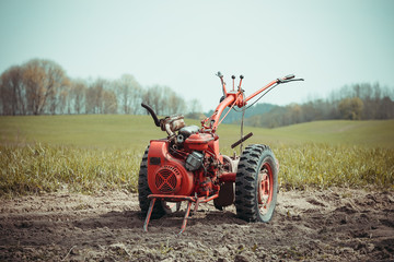 A small hand tractor, walk-behind tractor, plows the land. Work on the field. The concept of agriculture and industry