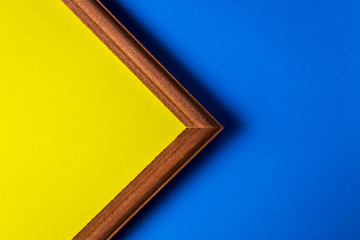 Wooden frame on a blue background. Inside the frame is a yellow background. The frame occupies half the space. empty space for an inscription.