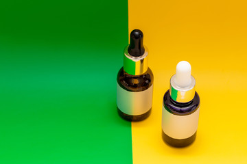 glass bottles for cosmetics, natural, essential oils or other liquids isolated on a orange, green background, copyspace