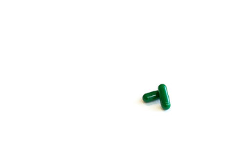 Closed green capsule pills on a white background.Concept of medicine