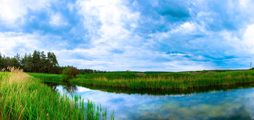 Naklejka na ściany i meble Landscape of a small pond during a cloudy sunset, panorama of the nature of the country