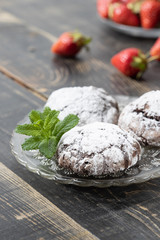 Homemade chocolate crinkles and strawberry in a glass saucer.