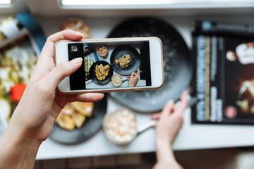 Woman taking a photo of breakfast with smartphone, hands hold phone, frome above