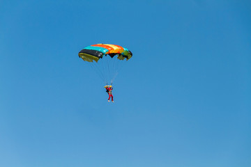 human silhouette running a colorful parachute in the blue sky