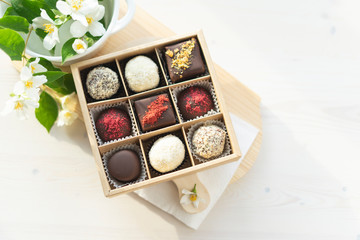 A box of chocolate mix of chocolates stands on the table in the morning light. Beautiful sweet gift for the wedding, for the birthday, for the holiday