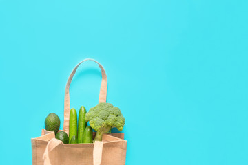 Green vegetables in eco-friendly recycled shopping bag on blue background