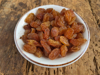 dried grapes in a bowl on a wooden table