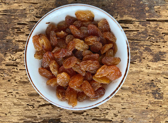 dried grapes in a bowl on a wooden table