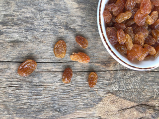 dried grapes in a bowl on a wooden table