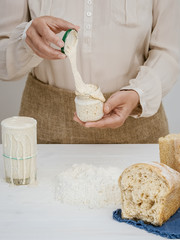 Baker woman holds a jar in her hands with ready-made sourdough for baking bread. Close-up. Home...